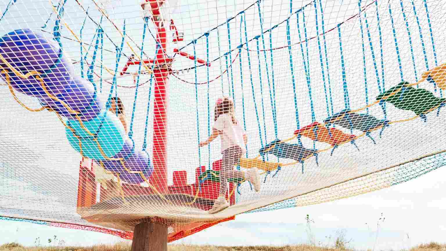 Participants engaging in a high-level rope course with obstacles, emphasizing teamwork and physical coordination in an adventure setting